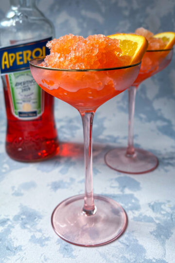 Aperol spritz granita served in a glass with fluffy frozen crystals and an orange slice