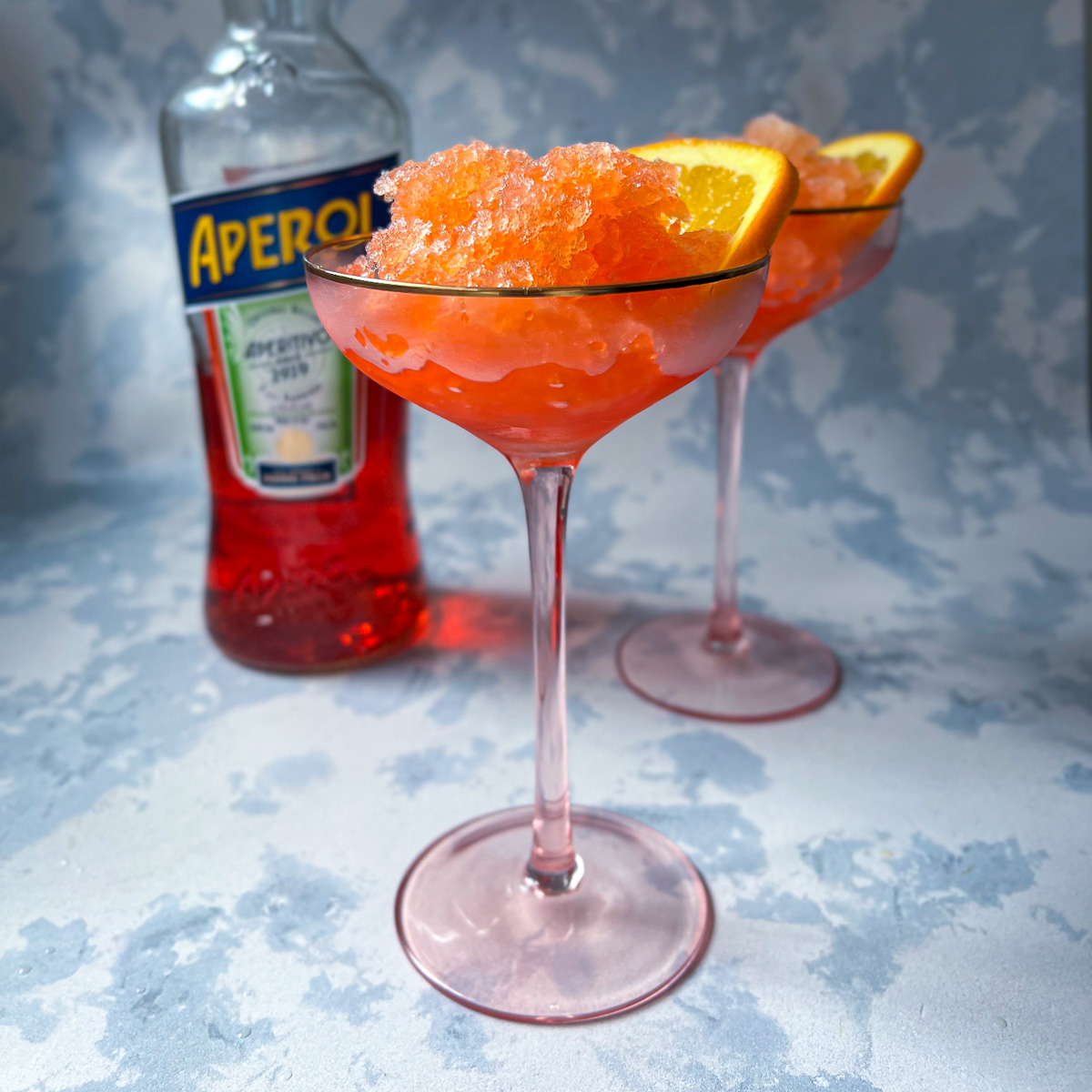 Aperol spritz granita served in a glass with fluffy frozen crystals and an orange slice
