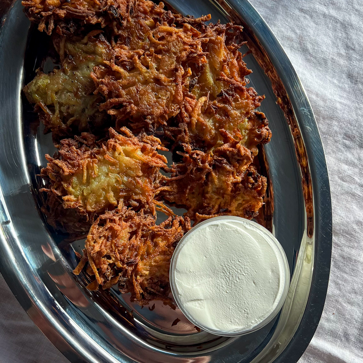 Crispy potato latkes on a silver platter