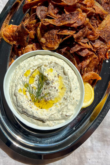 Creamy horseradish smoked trout dip topped with fresh dill and black pepper on a silver platter.